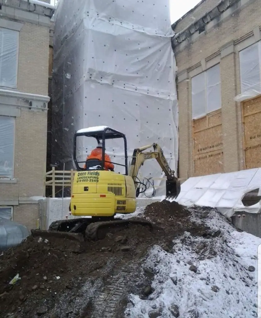 Mini excavator working beside a building by Josh Field Landscaping