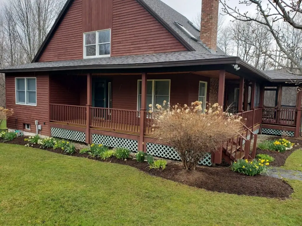 Foundation plantings along a farmhouse porch by Josh Field Landscaping