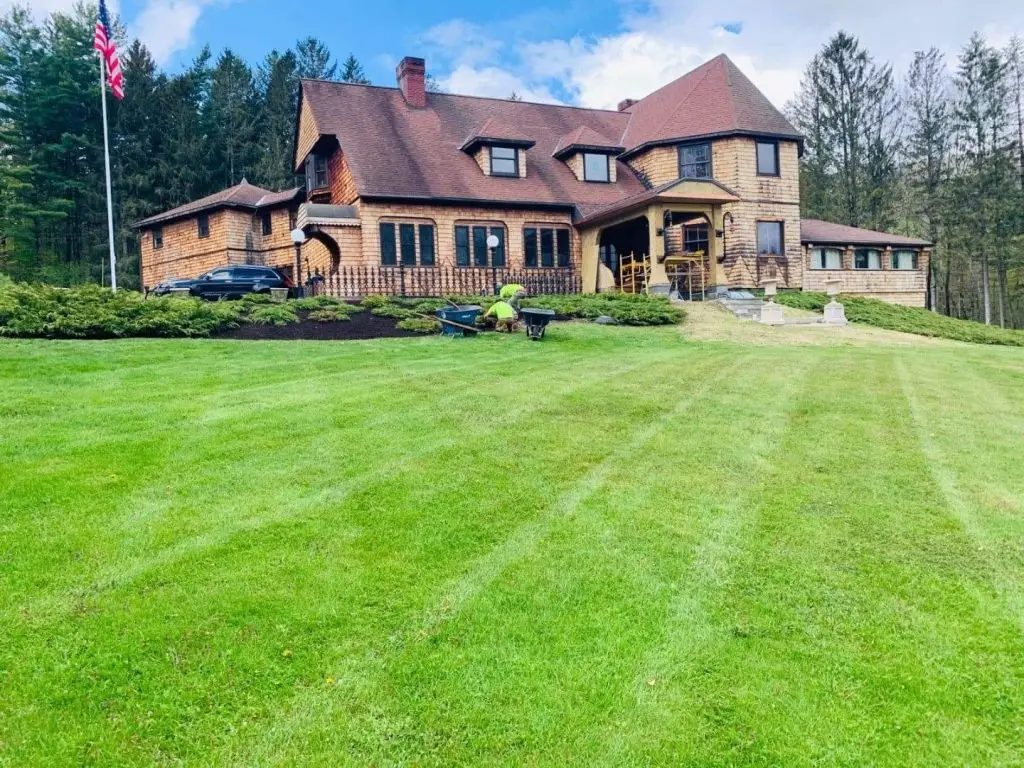 Striped lawn in front of a large estate home by Josh Field Landscaping