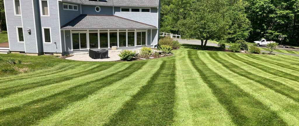 Freshly striped lawn in front of a home with a sunroom by Josh Field Landscaping