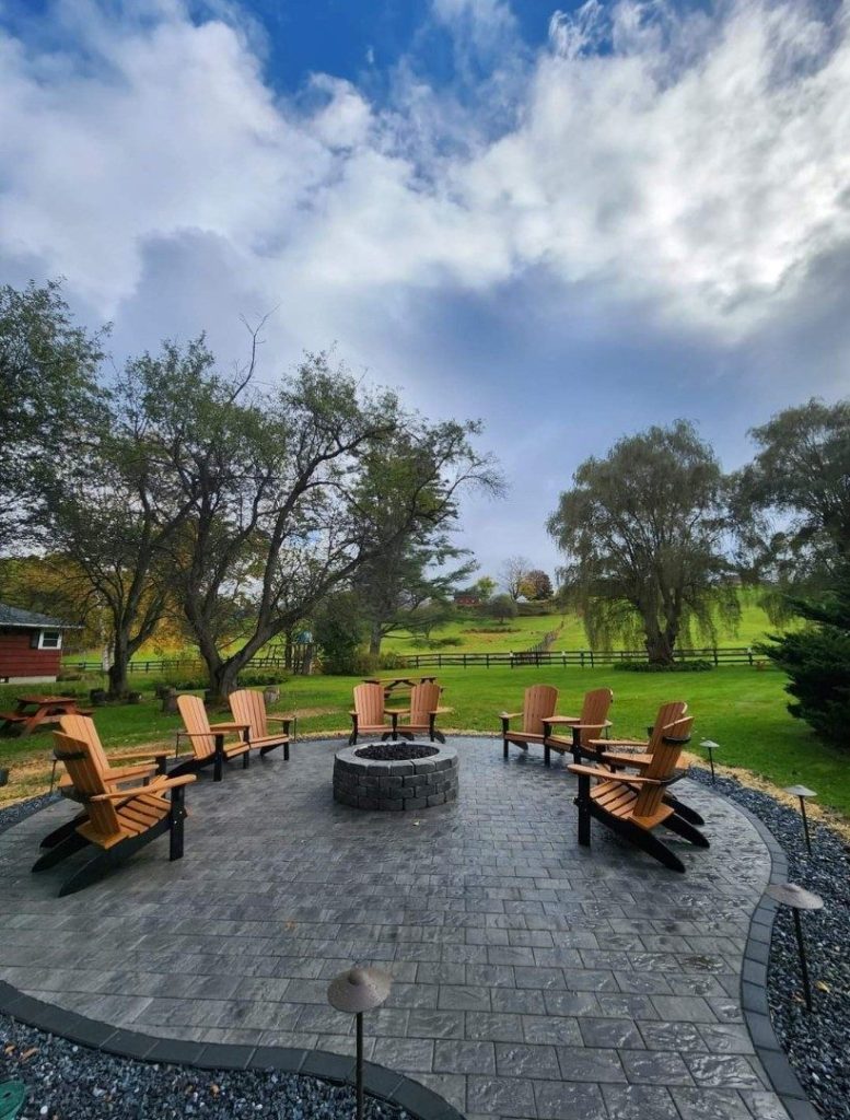 Circular patio with fire pit and Adirondack chairs by Josh Field Landscaping