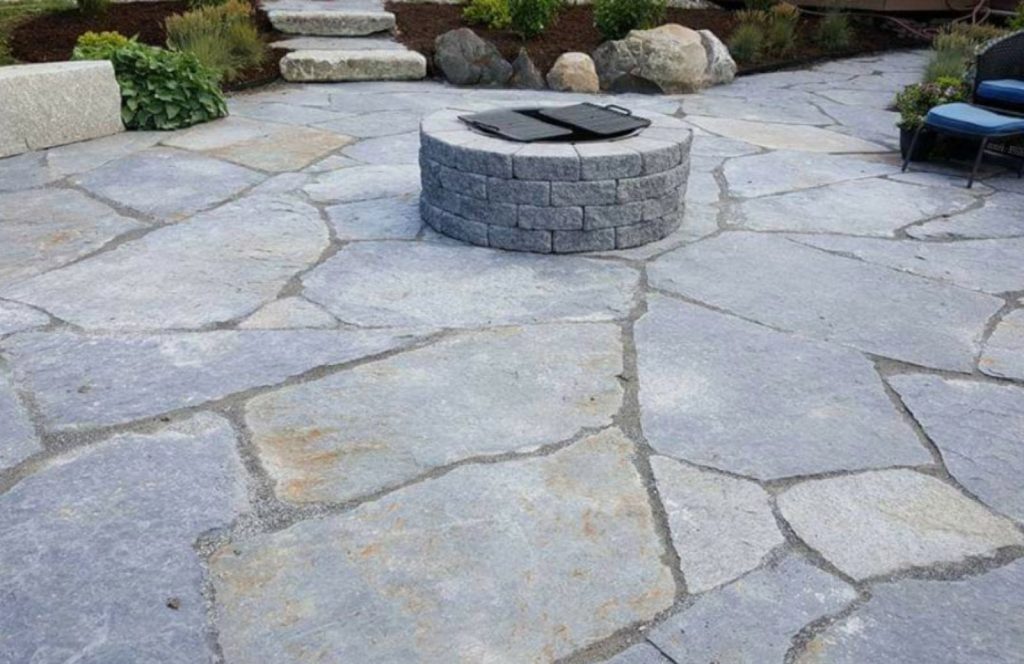 Flagstone patio around a block fire pit by Josh Field Landscaping
