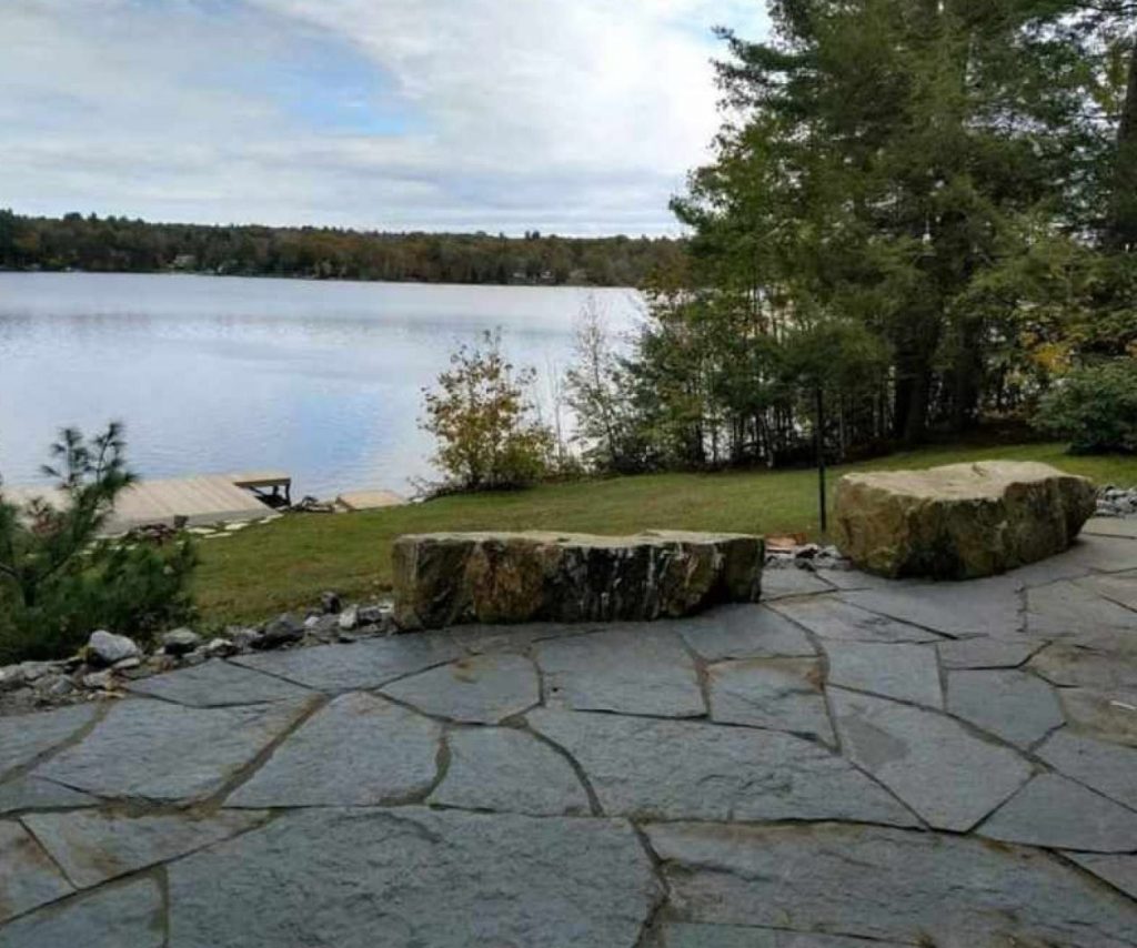 Flagstone patio with boulder seating on a lake by Josh Field Landscaping