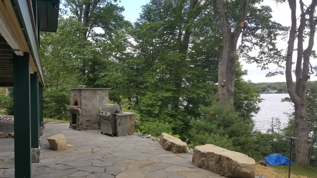 Lakeside stone patio with outdoor oven by Josh Field Landscaping