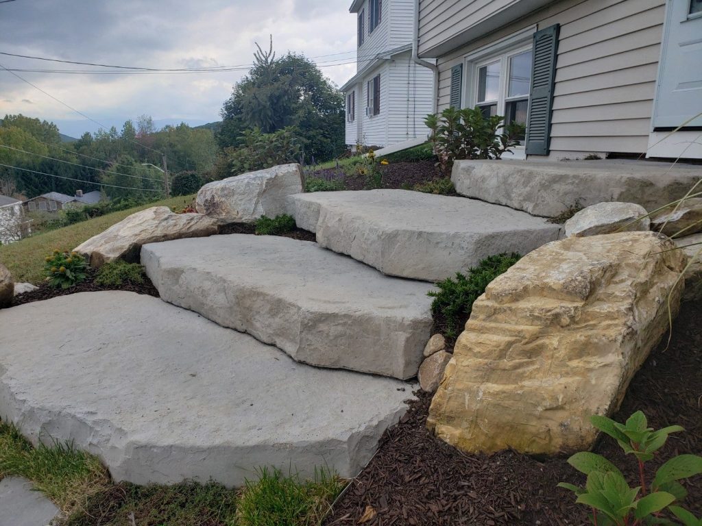 Large slab stone steps with a boulder by Josh Field Landscaping